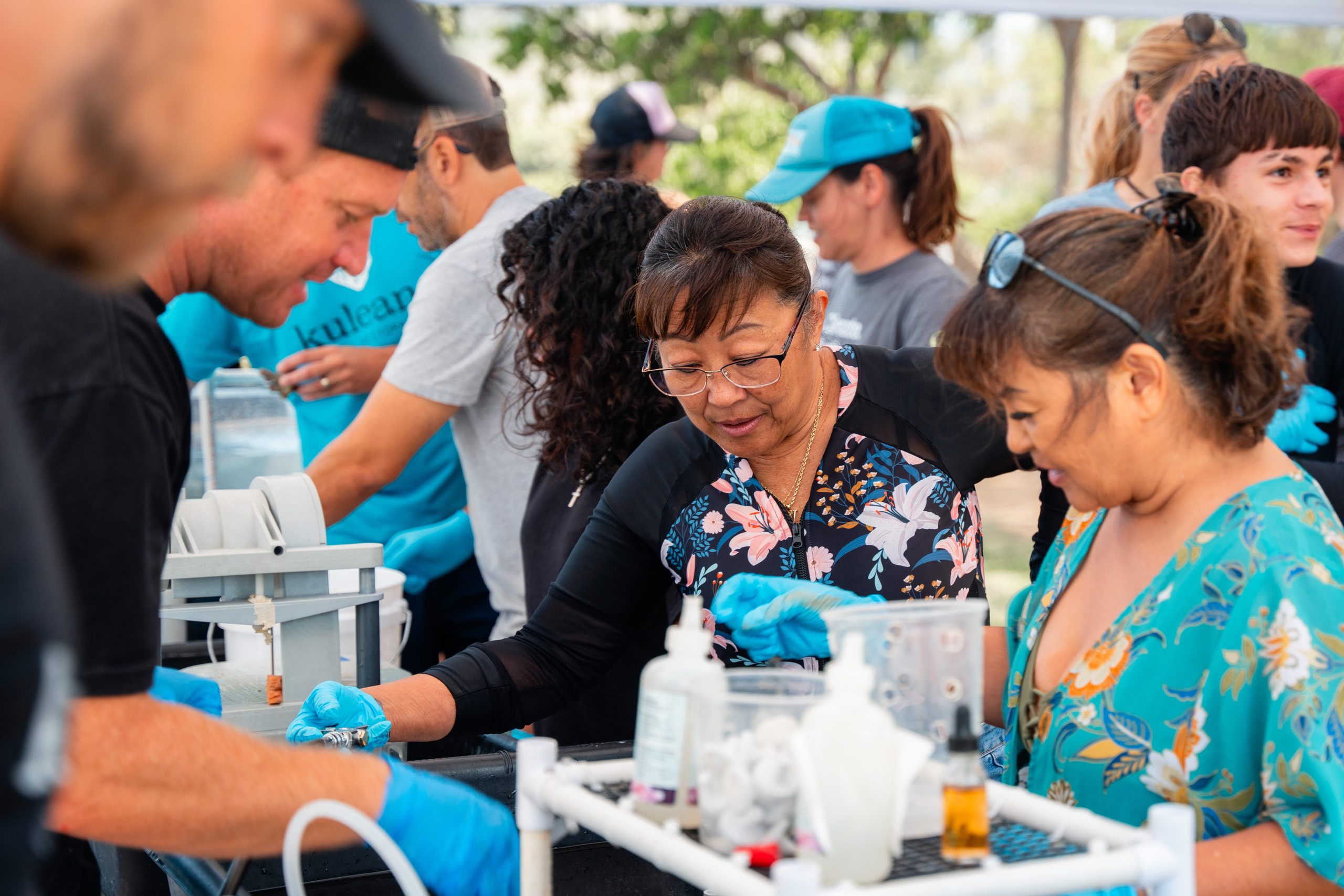 A group of people gathered around a table, engaging in conversation while water is placed on the table.